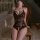 Woman wearing manyan pure & seductive halter lace bodysuit, black floral lace with open-crotch design, seated on vintage chai...