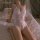 Woman in white lace halter bodysuit with open crotch, kneeling on bed — manyan pure & seductive sleepwear for date night.
