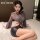 Woman wearing manyan sexy lace bodysuit - sheer office uniform dress with backless design & side-slit waist accent, posing on...