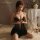 Woman wearing black manyan sheer lace sleep dress with adjustable straps and open front, styled in a romantic bedroom setting...