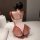 Woman in pink meimei flirty lingerie set, open-crotch bodysuit with ruffled sleeves and bow back, kneeling on bed.