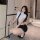 A woman poses in a stylish outfit featuring a white blouse with a black tie and a form-fitting black skirt, perfect for role ...