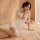 Woman in white lace bodycon dress with deep v-neck, posing on bed—meiyoujia sexy secretary costume sleepwear.