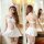 Woman modeling white nurse costume with red cross cap, bustier dress, lace stockings in bathroom mirror view.