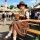 A woman wearing a traditional bavarian festival costume hat, complete with braided hair style, sits at an oktoberfest event h...