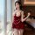 A woman poses elegantly in a luxurious red velvet sleep dress with lace detailing and pearl accents, perfect for festive occa...