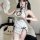 A woman poses wearing a white lace cheongsam sleepwear set, featuring a peek-a-boo cut-out bra and matching panty ensemble, e...