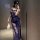 Woman in navy lace lingerie set with sheer floral pattern, holding white feather accessory, posing in mirror selfie.
