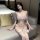 Woman wearing white lace lingerie set with bows, featuring bra and panty from night desire collection, seated on sofa.