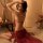 A woman poses elegantly in a sheer red bridal lingerie set, featuring intricate embroidery and a flowing design reminiscent o...