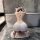 Woman in white night-ser lingerie set kneeling by bathtub, showcasing seductive backless design for passionate nights.