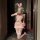 A woman poses in a playful bunny-themed outfit, featuring a pink bustier set with lace details and thigh-high stockings, hold...