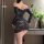 Woman wearing black lace bodycon mini dress with sheer long sleeves and one-shoulder design, posing in elegant room setting.