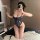 Woman wearing night silk lace bodysuit, sheer cut-out lingerie with adjustable straps and underwire, posing in bedroom.