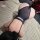 Woman wearing black sheer night silk lace bodysuit with cut-outs and adjustable straps, lying on fluffy rug beside red roses.