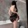 Woman wearing black lace sleep dress set in bathroom, sheer lingerie with floral details.