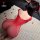 Woman wearing red mesh night silk seductive maid costume set, lying on white rug with rose petals, back view.