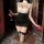 Woman in black and white night-silk seductive secretary outfit, holding a glass of wine, kneeling on a cushion.