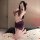 Woman wearing purple night silk sensual lace bodycon mini dress with sheer mesh, posing on bed with rose petals.