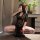 A woman poses in a luxurious setting, wearing a black lace dress with high slits and floral details. the elegant design featu...