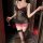 Woman wearing black sheer mesh lingerie set with pink lace trim, holding wine glass in dimly lit room.