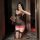 Woman in black sheer mesh lingerie set with pink lace trim, holding wine glass while taking mirror selfie.