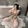 A woman poses in a bathroom wearing a night silk sexy maid costume, featuring a flirty chef cosplay outfit with ruffled hem a...