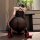 Woman in black night temptation sheer lace bodycon mini dress, kneeling with red-soled heels and rose nearby.