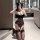 Woman kneeling in bathroom wearing black sheer mesh lace lingerie set with thigh-high stockings, holding phone to face.