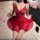 Woman wearing red lace mesh sleep dress with strappy design, sheer provocative lingerie nightgown on bed with rose petals.