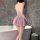 Woman wearing shiny pink nightse lace slip dress, back view in modern bathroom with bathtub.