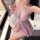 Woman wearing pink shiny nightse lace slip dress with deep v-neck and flared skirt, posing in bathroom.