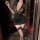A woman poses elegantly in a black floral lace dress with a deep v neckline, holding a glass. the outfit features sheer sleev...