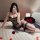 Woman wearing nightsi nightse sheer mesh lingerie set with black stockings, posing on bed with red roses.