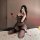 Woman in black sheer mesh nightsi lingerie set with stockings, holding red rose on bed.