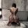 Woman wearing nightsi nightse sexy mesh bodysuit with open-crotch design and thigh-high stockings, shown from behind in a mod...