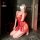 Woman kneeling in red nightsigh lace babydoll dress with tassels, sheer floral design, adjustable straps for date night.