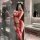 Woman in red nightsigh lace bodysuit with sheer mesh, halter neck, and cutouts, posing in a modern bathroom.