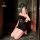 Woman kneeling in black lace bodysuit and sheer mesh skirt set with bunny ears headband, holding phone to face.