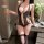 Woman wearing black lace lingerie set with sheer panels, holding a glass. nightsigh lace lingerie set for intimate moments.