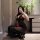 Woman in black sheer nightsigh nightseduce lingerie set, posing with rose and phone, elegant bedroom setting.