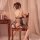 Woman wearing black sheer mesh nightsigh nightseduce lingerie set, sitting on wooden chair in romantic bedroom setting.