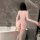 Woman in pink nightsigh nightseduction lingerie set with open-crotch design, standing by bathtub.