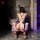 Woman in nightsigh nightsere sexy bunny costume - sheer lace bodysuit with ties & open-crotch design, kneeling by flowers.