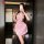 A woman poses in a pink polka dot maid outfit, featuring a backless design and ruffled skirt, perfect for a playful chef or l...