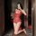 Woman kneeling in red lace nightsigh bodysuit, holding wine glass while taking mirror selfie.