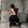 Woman in nightsigh nightsilk ol secretary outfit, featuring a curvy bodycon skirt and sleeveless top, posing with phone in mo...