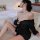 Woman wearing black sheer off-shoulder nightsigh lingerie set with pearl straps, posing on bed in sensual nightgown style.