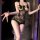 Woman wearing black lace bodysuit with floral trim, sheer mesh, open-crotch design, and vintage uniform-style straps.