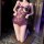 Woman kneeling in purple night night lace bodysuit with floral trim and open-crotch design.